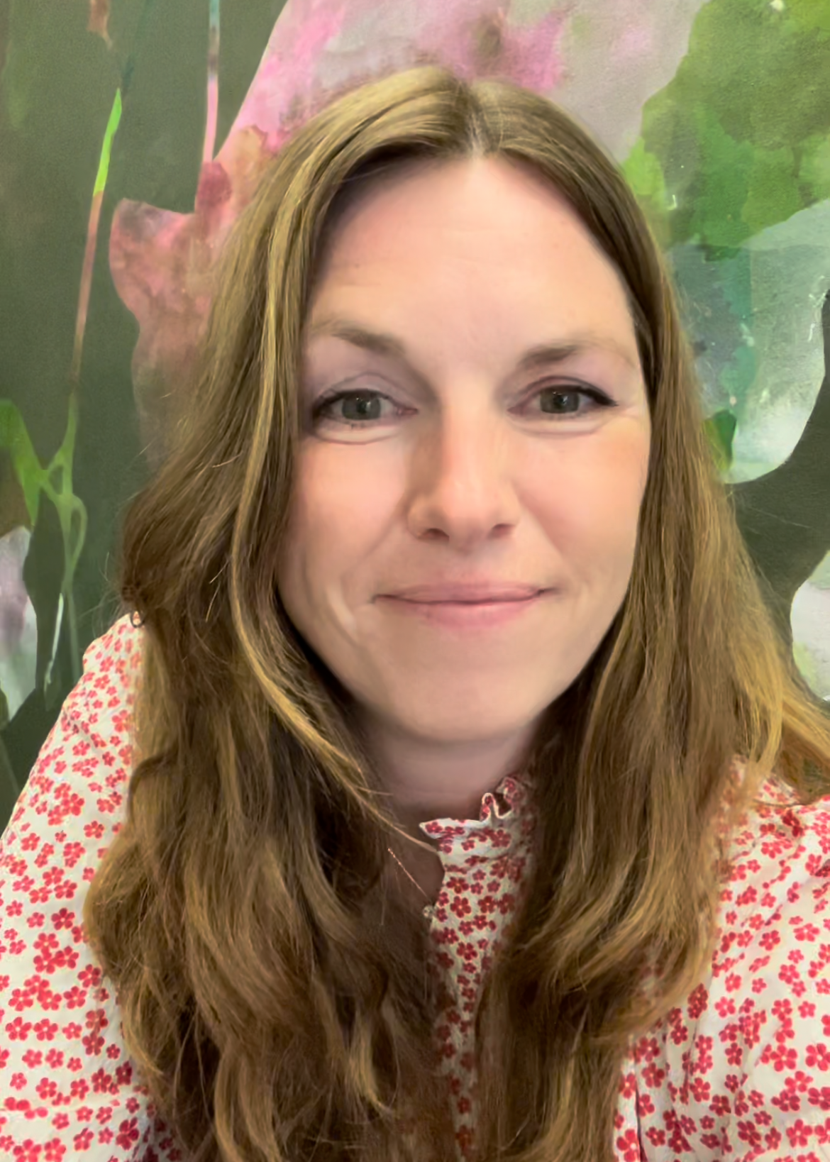 Ida Kopperud wearing a red floral blouse in front of an abstract painting.