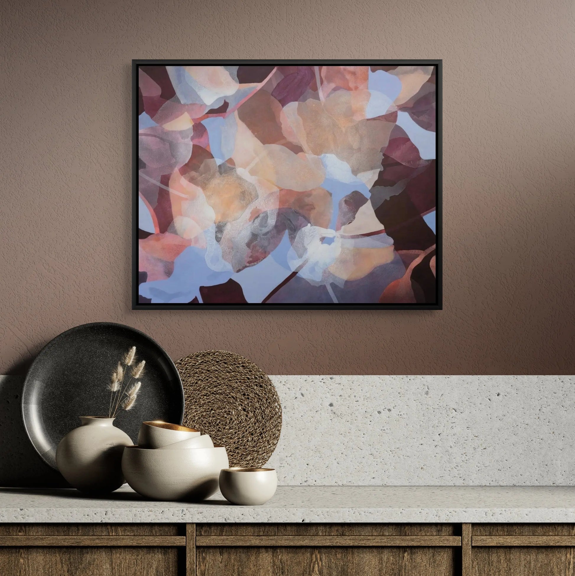 Abstract art piece on a wall above a wooden cabinet with decorative items.