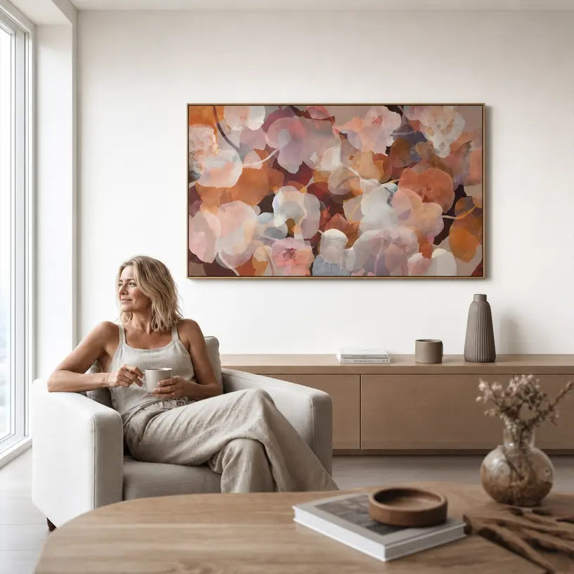 Woman sitting in a modern living room with a large abstract painting on the wall.