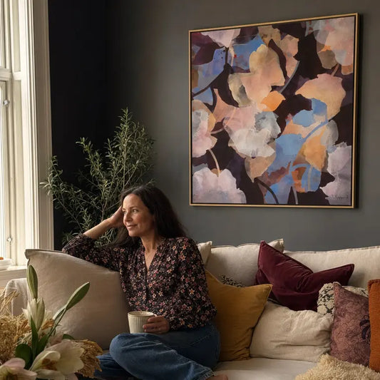 Woman sitting on a couch in a living room with a colorful abstract painting on the wall.