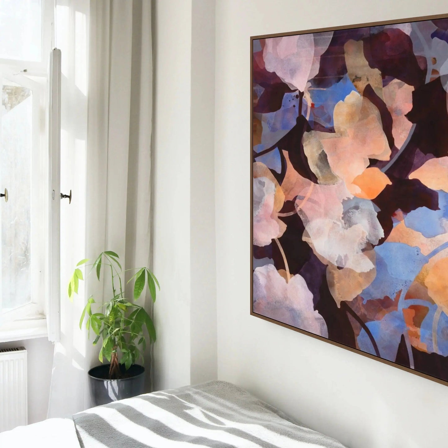 Abstract painting on a wall above a bed with a plant beside a window.