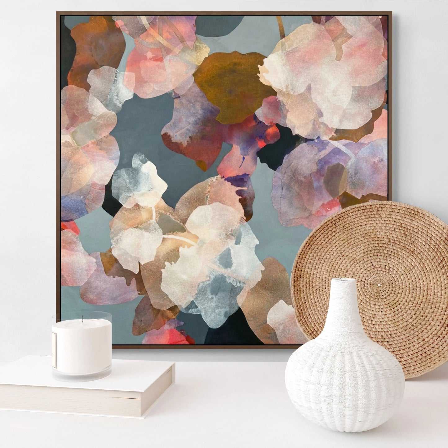 Framed abstract floral artwork on a wall with decorative items below.