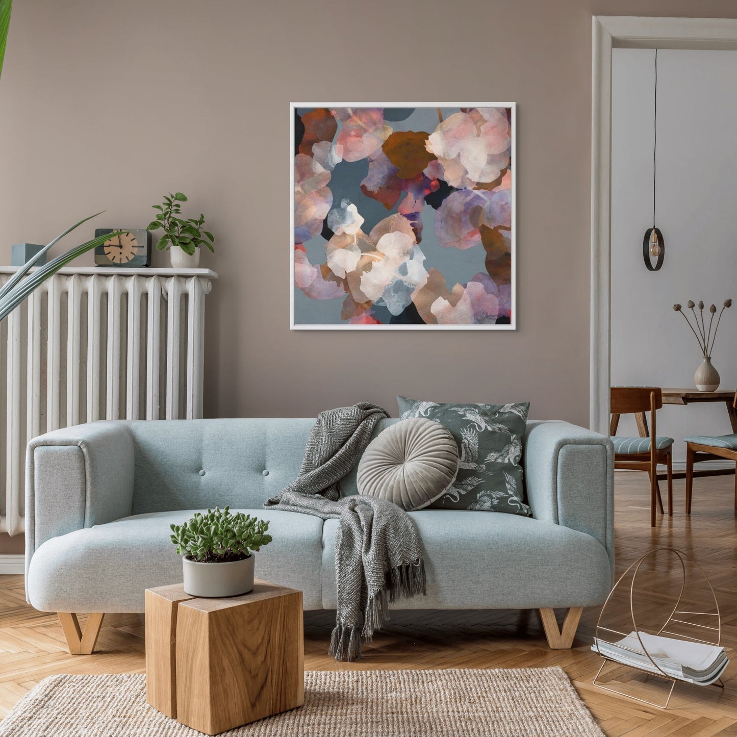 Modern living room with a light sofa, decorative pillows, and abstract colorful art on the wall.